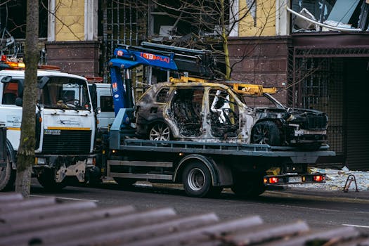 A burnt car is towed on a street in Kyiv, highlighting the aftermath of conflict.